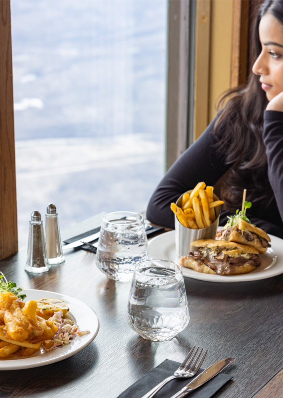 A guest with entrees set on the table, looking at the view from the Summit Cafe.