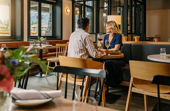 A couple sits at a table at Farm & Fire and enjoys glasses of wine.