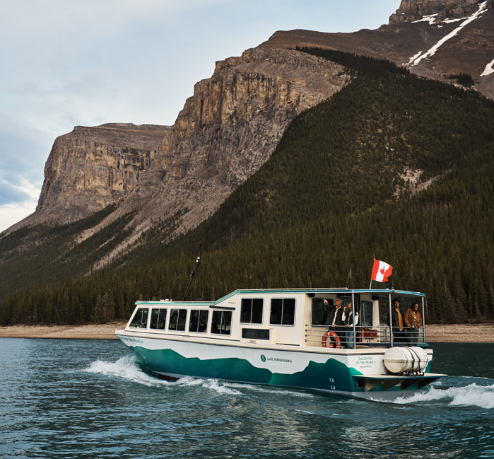 A Lake Minnewanka Cruise sailing passed the coastline and mountains.