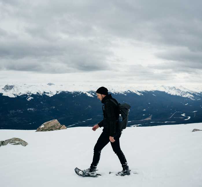 A person snowshoeing on top of a mountain in Jasper