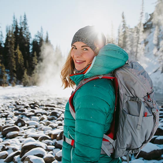 A hiker at a snow covered riverside.