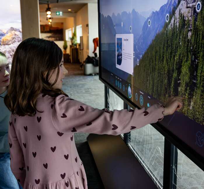 The entrance to the Above Banff Interpretive Centre posted on tree, surrounded by rocks and educational displays