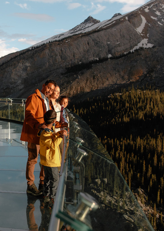 A family standing on the Columbia Icefield Skywalk, looking at the mountain view.