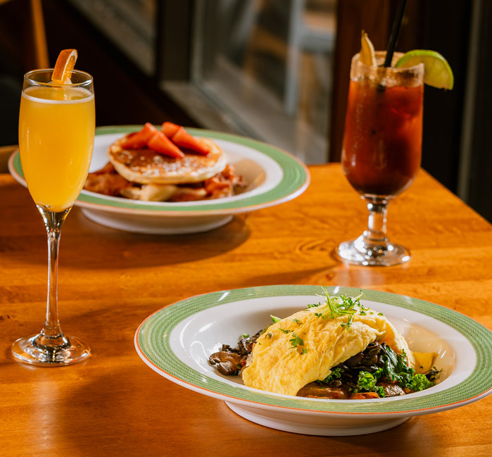 Breakfast dishes served with a mimosa and Caesar