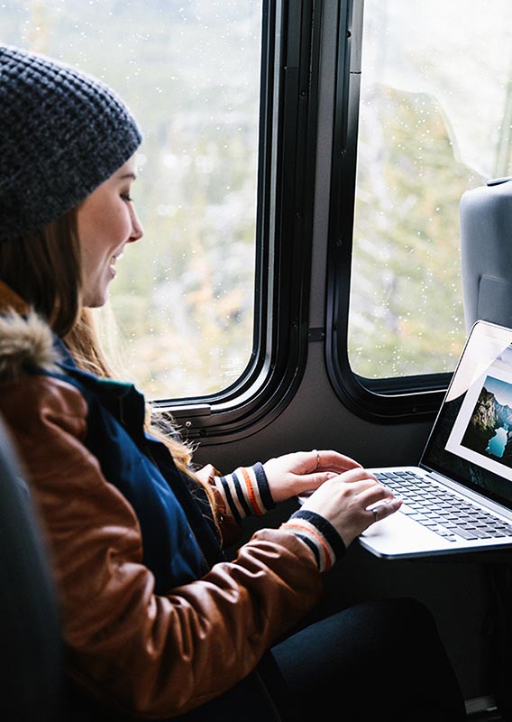 Lady seated on Brewster Express reviewing photos from her trip on her laptop