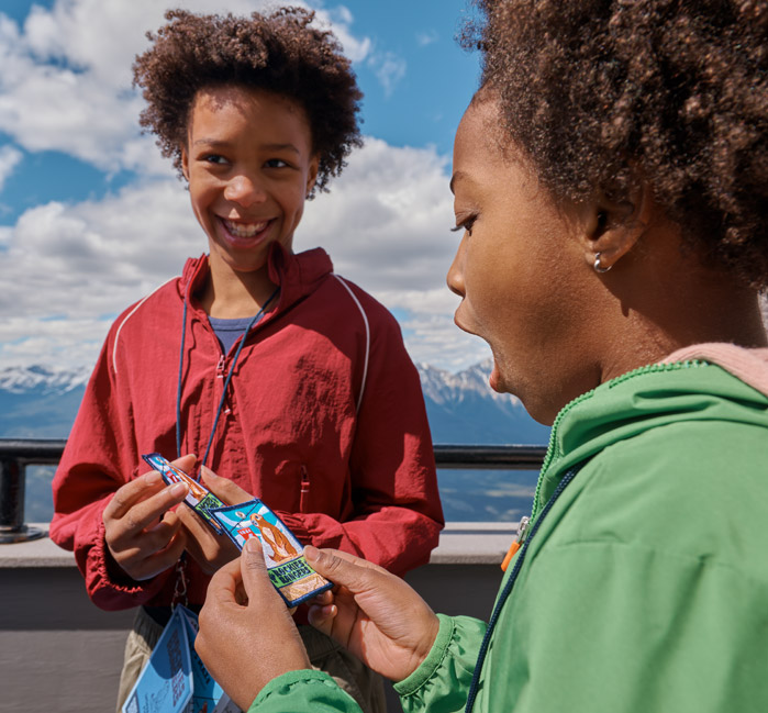 Two kids at the Jasper SkyTram, looking at their Rockies Rangers badges.