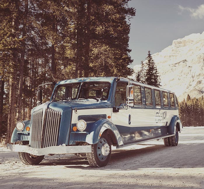 A historic-style touring auto stopped on a snowy road.