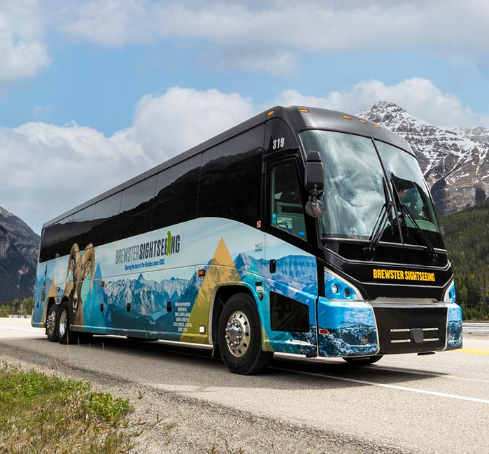 A coach bus on a road below mountains.