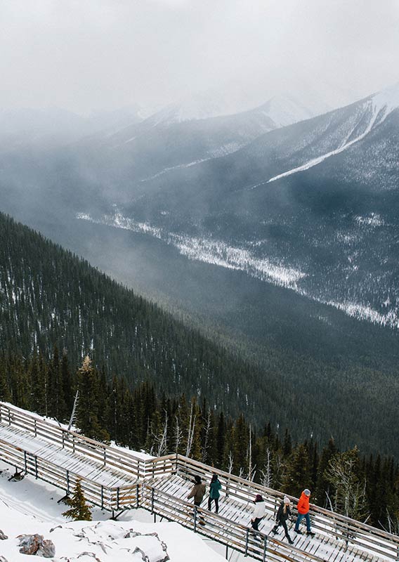 People walk along the Banff Gondola boardwalk in the winter.