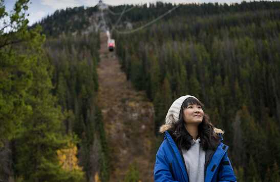 Person standing at base of Jasper SkyTram with tram descending above